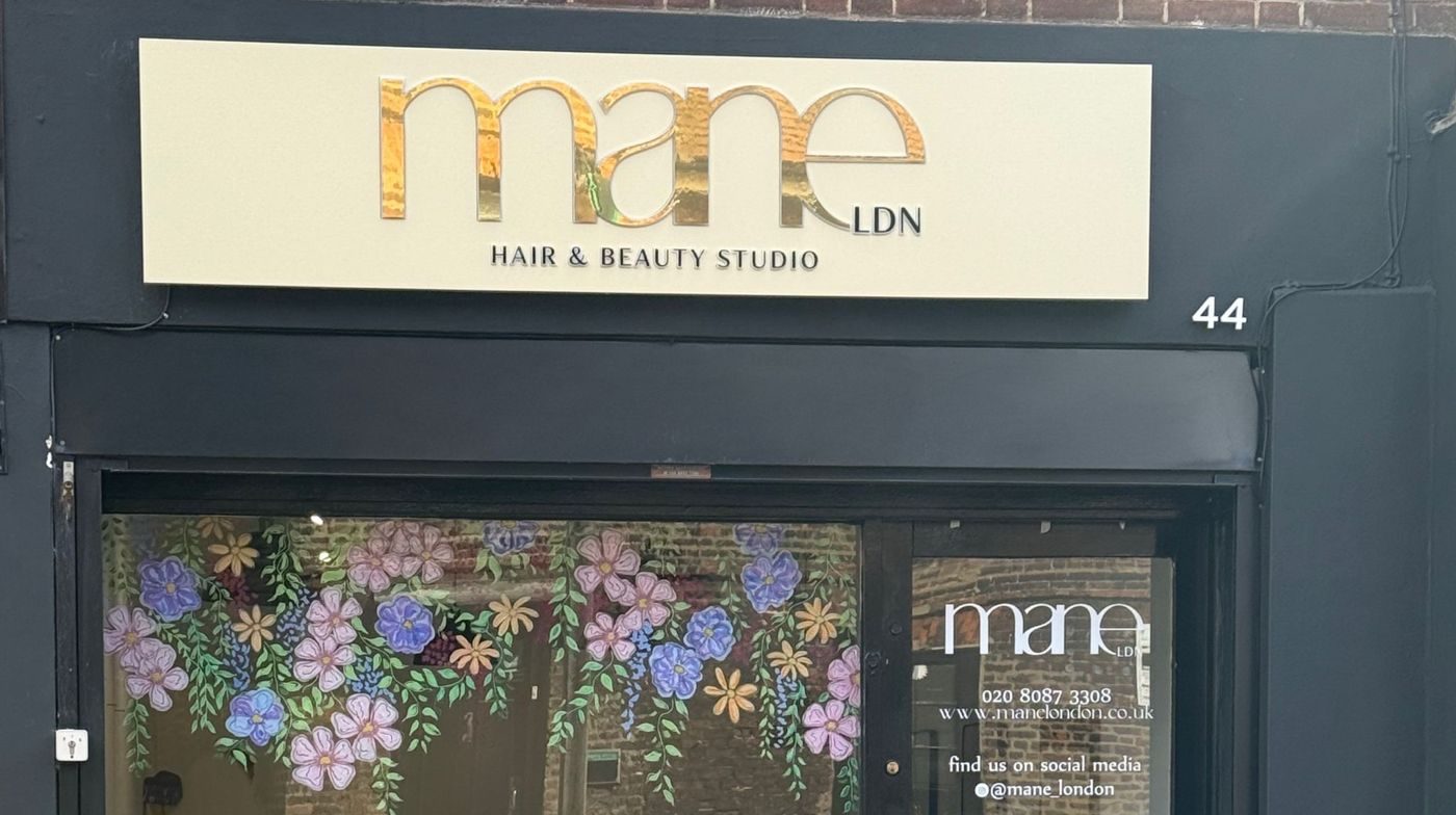 The Mane London shopfront: a black front, cream sign with the gold mane logo and a flower-painted window